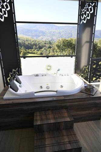 eine weiße Badewanne in einem Zimmer mit einem großen Fenster in der Unterkunft La Ruota Hotel Sharr in Dragash