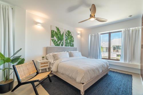 a bedroom with a bed and a chair and a window at Casa Brisa & The PoolClub at Mahogany Bay! in San Pedro