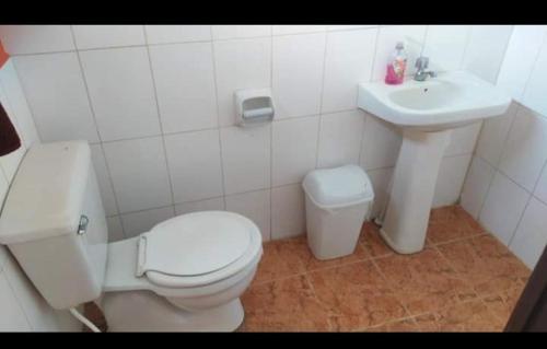 a white bathroom with a toilet and a sink at Posada del Abuelo in Torotoro