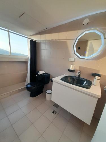 ein Badezimmer mit einem Waschbecken, einem WC und einem Spiegel in der Unterkunft Executive Style Condo With Sea Views in Porlamar
