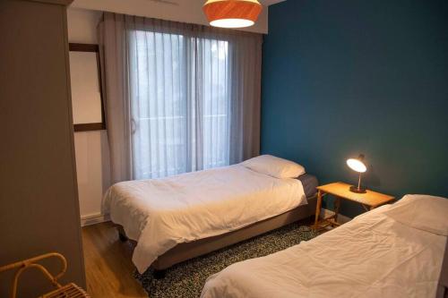 ein Schlafzimmer mit 2 Betten und ein Fenster mit einer Lampe in der Unterkunft Appartement Arcachon en 1ère ligne face à la mer in Arcachon