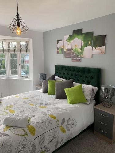 a bedroom with a large bed with a green headboard at NEC/Airport - The Allium, Two bedroom apartment in Marston Green
