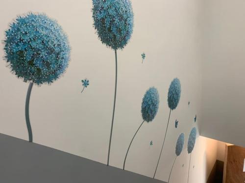 a painting of blue dandelions on a wall at NEC/Airport - The Allium, Two bedroom apartment in Marston Green