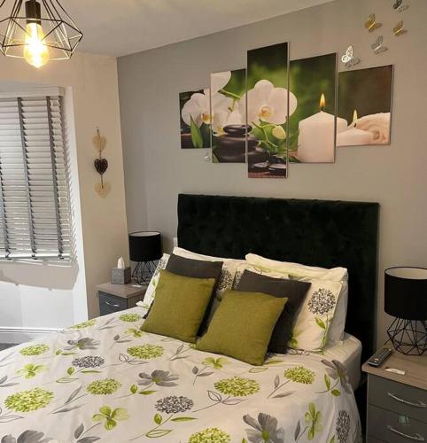 a bedroom with a large bed with green pillows at NEC/Airport - The Allium, Two bedroom apartment in Marston Green