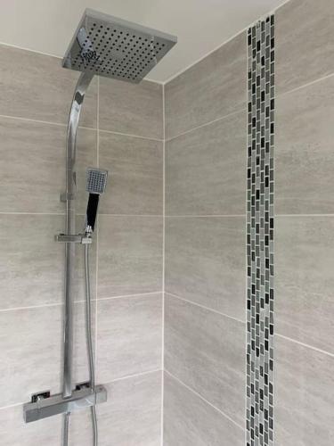 a shower with a shower head in a bathroom at NEC/Airport - The Allium, Two bedroom apartment in Marston Green
