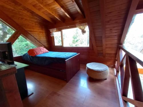 - une chambre dans une cabane en rondins avec un lit et un tabouret dans l'établissement Mutisia Puerto Manzano, à Villa La Angostura