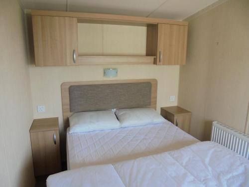 een kleine slaapkamer met een bed en kasten bij Kingfisher Bordeaux 8 Berth Central Heated FREE WIFI in Ingoldmells