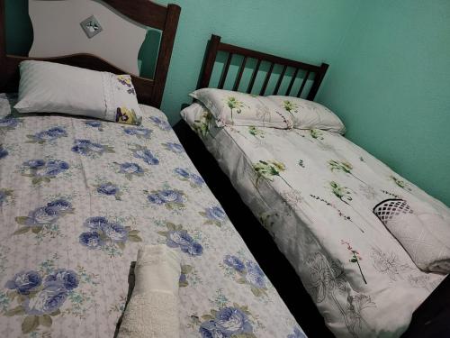 a bedroom with two twin beds with blue flowers at Casa inxalmel in Blumenau