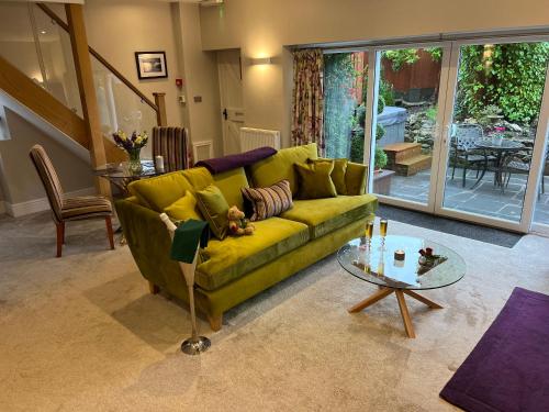 a living room with a green couch and a glass table at Windermere Boutique Hotel Spa Suites & Hot Tubs in Windermere
