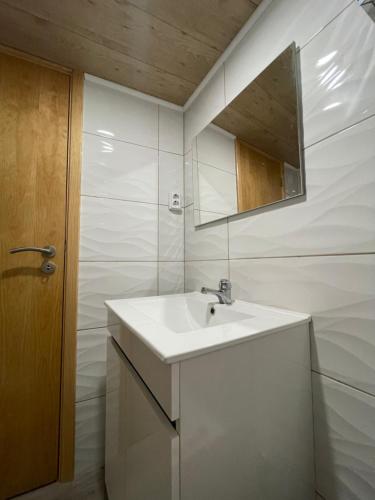 ein weißes Badezimmer mit einem Waschbecken und einem Spiegel in der Unterkunft Abrigo do Outeiro - Serra Da Estrela in Cabeça