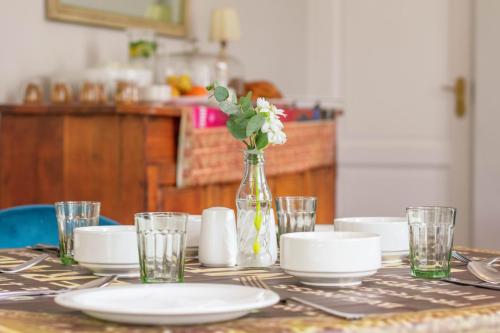 una mesa con platos y un jarrón con flores. en Rozenburg Guest House, en Stellenbosch