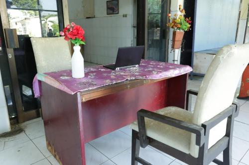 een paarse tafel met een vaas met bloemen en een laptop erop bij OYO 93159 Homestay Sehat in Gresik