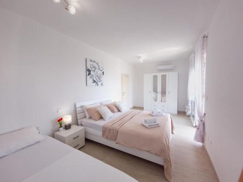 ein weißes Schlafzimmer mit 2 Betten und einem Fenster in der Unterkunft Modern villa with jacuzzi, beautiful sea view, near Split! Villa 36A in Podstrana