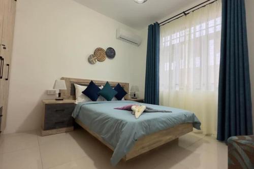 a bedroom with a bed with blue curtains and a window at SeaSand-Entire Luxury 3 BD condo - Close to beach in Flic-en-Flac