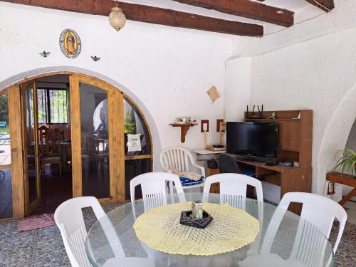 Quinta Lachaud في Chiconcuac: غرفة طعام مع طاولة زجاجية وكراسي بيضاء