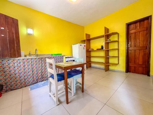 une cuisine avec une table et un mur jaune dans l'établissement Barra Quintal - Studio 2, à Barra Grande