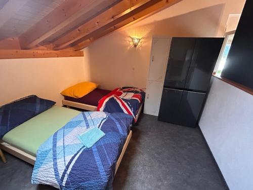 Habitación pequeña con 2 camas y nevera. en Gite la Cigale lit en dortoir, en Saxon