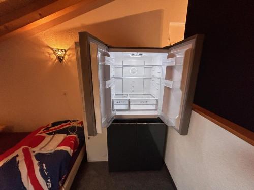 un frigorifero vuoto con la porta aperta in una stanza di Gite la Cigale lit en dortoir a Saxon