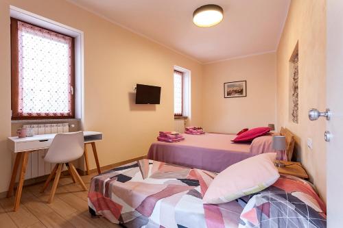 two beds in a room with a desk and a table at Veruskacamere Camera 2 in Somma Lombardo