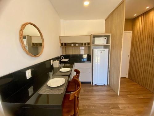a kitchen with a black counter top and a mirror at Vila do Centro Bombinhas in Bombinhas