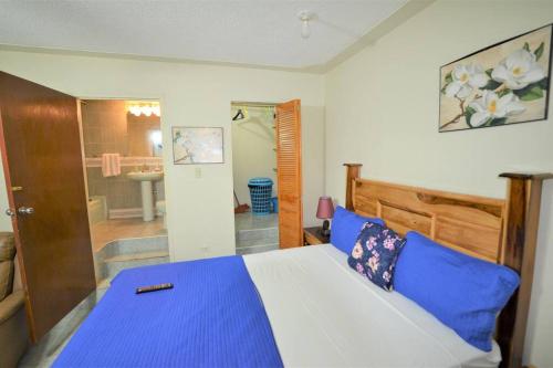 Un dormitorio con una cama azul y blanca y un baño. en Cozy Locale Pearl en Port Antonio