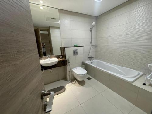 a bathroom with a tub and a toilet and a sink at Lovely New 1 bed Apt - Mirdif Hills Avenue in Dubai