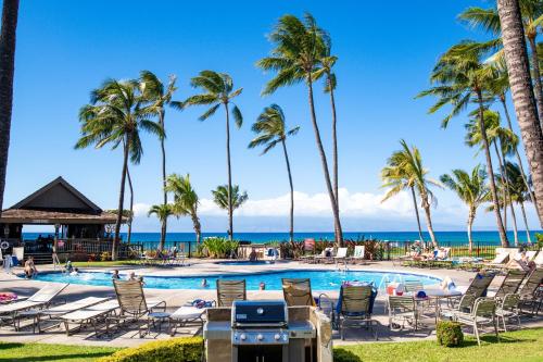 a swimming pool with palm trees and the ocean at Papakea #F108 condo in Kahana