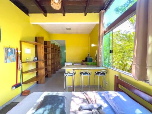 une chambre jaune avec un lit et une cuisine avec un comptoir dans l'établissement Barra Quintal Studio 3, à Barra Grande