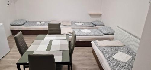 Cette chambre comprend 4 lits, une table et des chaises. dans l'établissement Andrea ubytovanie, à Štúrovo