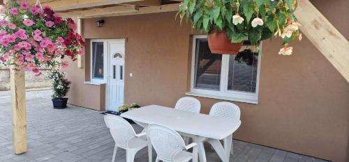 什圖羅沃的住宿－Andrea ubytovanie，鲜花庭院里的白色桌子和椅子