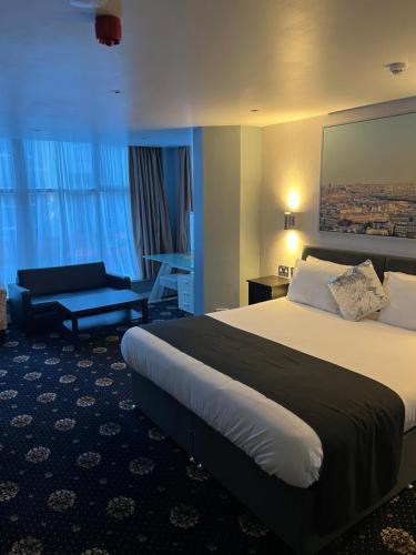 a hotel room with a large bed and a chair at Shores Holiday Apartments in Blackpool