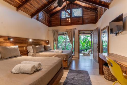 two beds in a room with wooden ceilings at Banana Beach Bungalows in Santa Teresa Beach