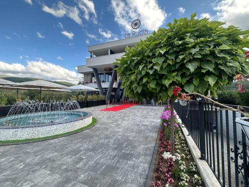a building with a fountain and flowers in front of it at La Ruota Hotel Sharr in Dragash
