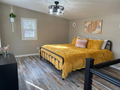 1 dormitorio con 1 cama grande con manta amarilla en 1970's Inspired Vacation Home 