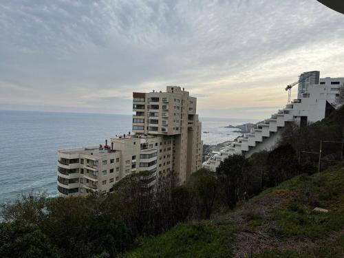een groep gebouwen op een heuvel naast de oceaan bij Reñaca departamento in Viña del Mar