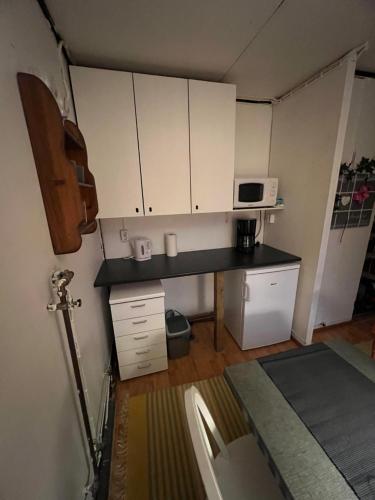 eine kleine Küche mit weißen Schränken und einer Mikrowelle in der Unterkunft Elämyksellinen majoitus farmilla in Kälviä