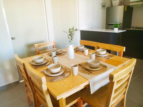 a wooden table with plates and dishes on it at Alberca, Playa Cercana & Club de Playa opcional -Departamento E13D302 in Gallinero