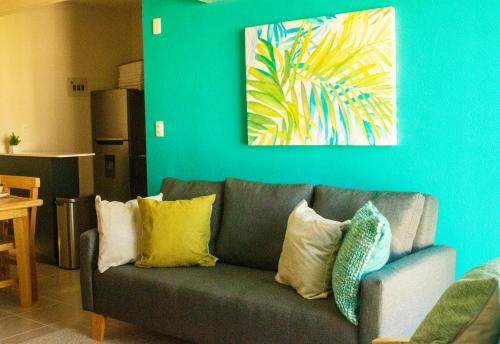 a couch in a living room with a painting on the wall at Alberca, Playa Cercana & Club de Playa opcional -Departamento E13D302 in Gallinero