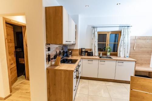 a small kitchen with white cabinets and a window at Haus Kogelleiten in Ramsau