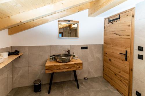 a bathroom with a sink and a wooden door at Haus Kogelleiten in Ramsau