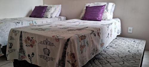 1 dormitorio con 2 camas individuales y almohadas moradas en Residencial mar do norte II, en Florianópolis