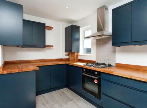 cocina con armarios azules y fogones en Stunning 5 bed with free parking, en Aldershot