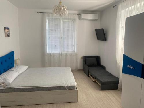 a bedroom with a bed and a couch and a window at Bluemoon-Apartment with Parking in Burgas