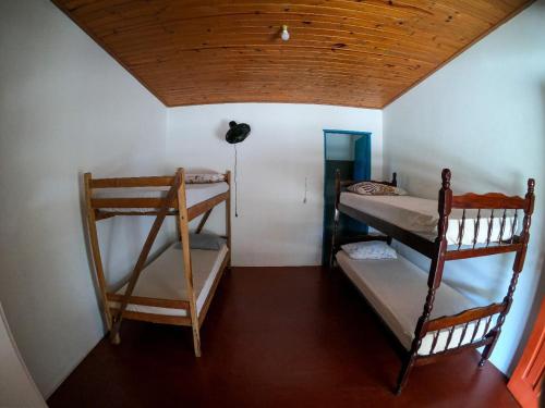 a room with two bunk beds and a wooden ceiling at Namastê Pousada e Camping in Cananéia