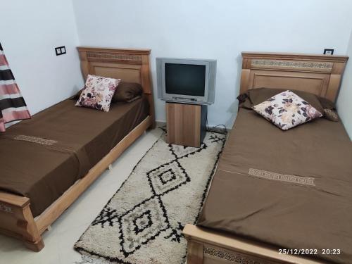 Cette chambre comprend 2 lits et une télévision sur une table. dans l'établissement Marrakech golf city, à Marrakech