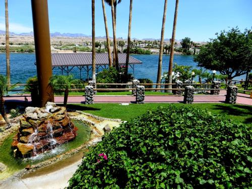 a fountain in a park with palm trees and water at The New Pioneer in Laughlin