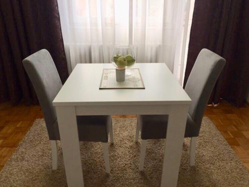 a white table with chairs and a vase of fruit on it at Matejevic Apartments in Niš
