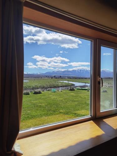 a window with a view of a field at Casa familiar Fellow - Casa de Bioconstrucción a 4 km de Trevelin in Trevelin