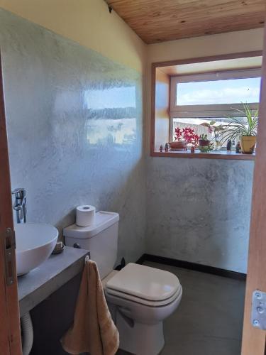 a bathroom with a toilet and a sink and a window at Casa familiar Fellow - Casa de Bioconstrucción a 4 km de Trevelin in Trevelin