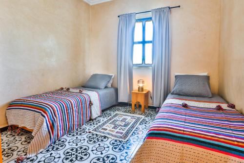 two beds in a room with a window at Maison Insa in Essaouira